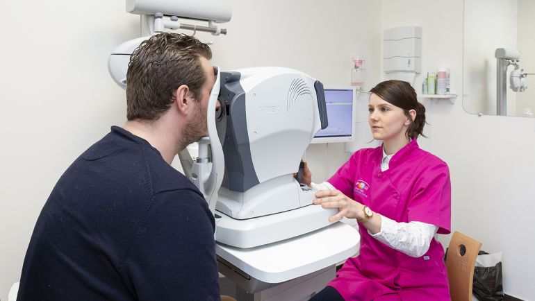 Une orthoptiste effectue un contrôle préliminaire : mesure de la réfraction objective et tension oculaire